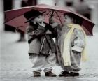 Çocuklar onu şemsiye ile yağmur altında yürümek